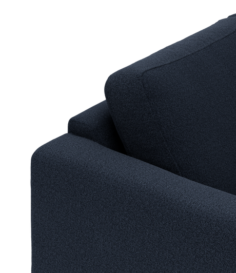 Nærbillede af mørkeblå stofsofa med armlæn og ryghynde.