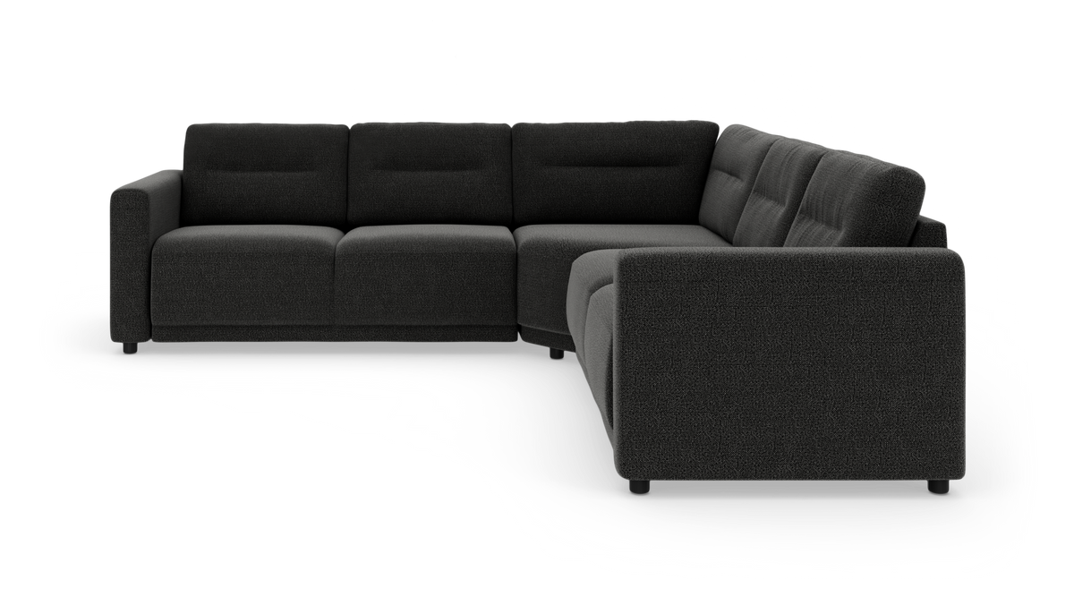 Mørkegrå L‑formet modulsofa i tekstil, vist i studiemiljø.