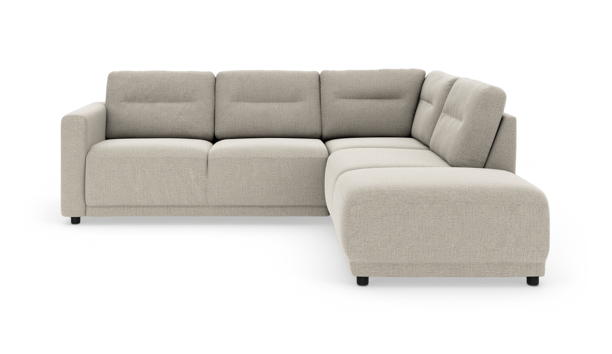 Beige L‑formet modulsofa i stof med lave sorte ben og bløde ryghynder, vist i studieopsætning.