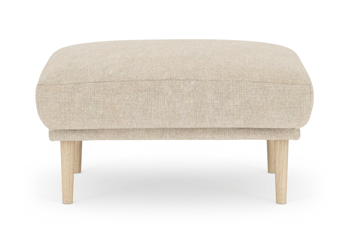 Beige skammel/ottoman med stofbetræk og lyse træben, frilagt på hvid baggrund.