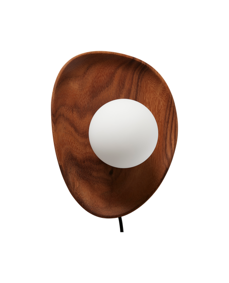 Beigefarvet lænestol med afrundede former i stuen, med pude og plaid, slank gulvlampe, lille sidebord med vase og bog, grøn plante, indrammet vægkunst, blødt tæppe og grå gardiner.