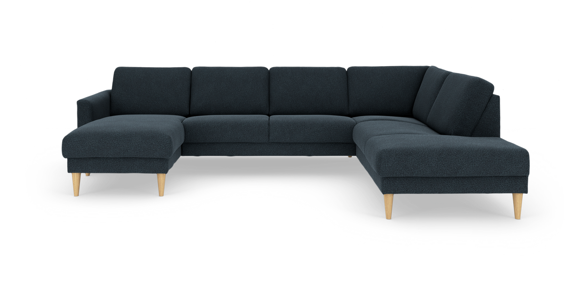 Mørkeblå U‑sofa i stof med chaiselong til venstre og koniske ben i lyst træ, frilagt på hvid baggrund.