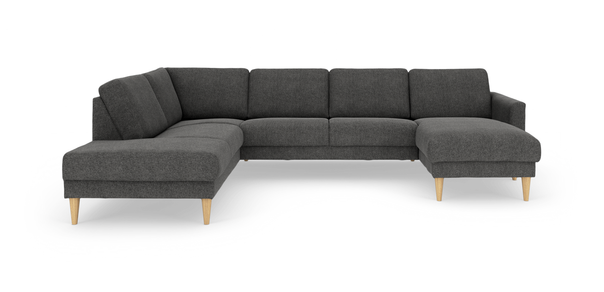 Mørkegrå hjørnesofa i stof med chaiselong og lyse træben, frilagt på hvid baggrund.