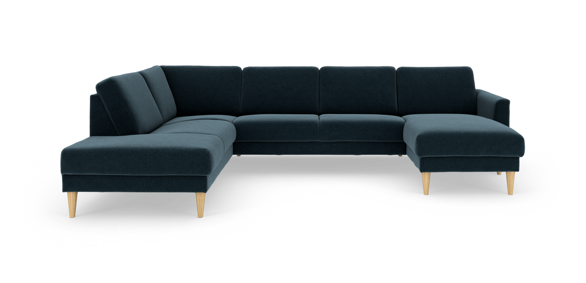 Mørkeblå hjørnesofa med chaiselong til højre og lyse træben, frilagt på hvid baggrund.