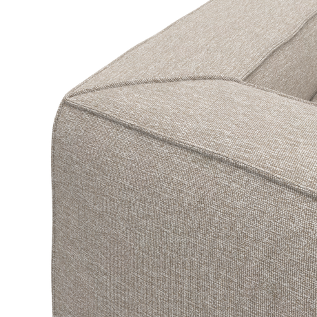 Nærbillede af hjørnet på en beige stofsofa med tydelig syning, frilagt mod hvid baggrund.