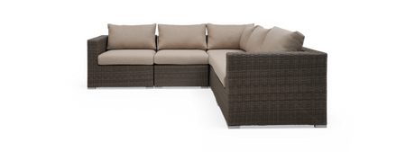 Modulær hjørnesofa i polyrattan med beige hynder, frilagt på sort baggrund.