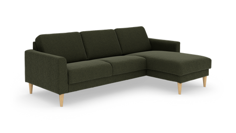 Mørkegrøn hjørnesofa med chaiselong til højre og lyse træben, frilagt på hvid baggrund.