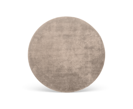 Rundt beige tæppe med blød, velourlignende tekstur på hvid baggrund.