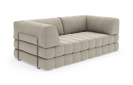 Beige modulsofa med kanalquiltet sæde og ryg, afrundede puder og en kromet sidestang, frilagt på hvid baggrund.