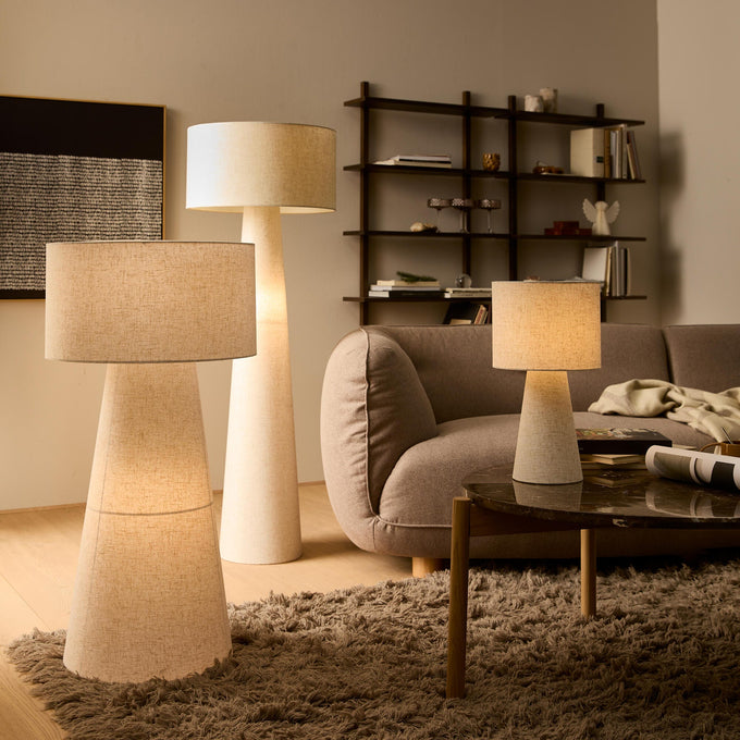 Tre beige lamper i en varm, skandinavisk stue med sofa, vægreol og blødt shaggy tæppe.