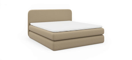 Beige polstret seng med hvid madras, produktbillede på sort baggrund i skrå frontvinkel.