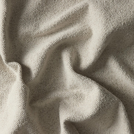 Nærbillede af beige boucléstof med blød, nopret struktur og folder.