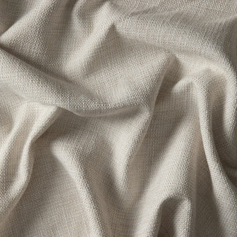 Nærbillede af beige vævet tekstil med bløde folder.