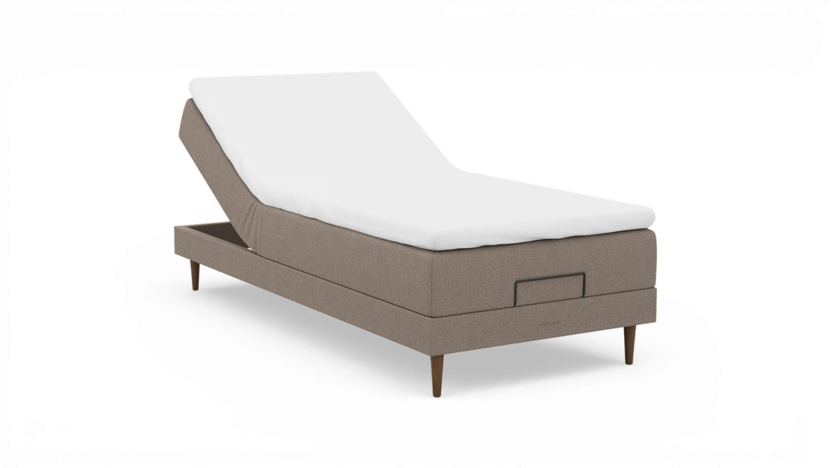 Beige justerbar seng med hvid topmadras og træben, nocturne-logo på soklen.