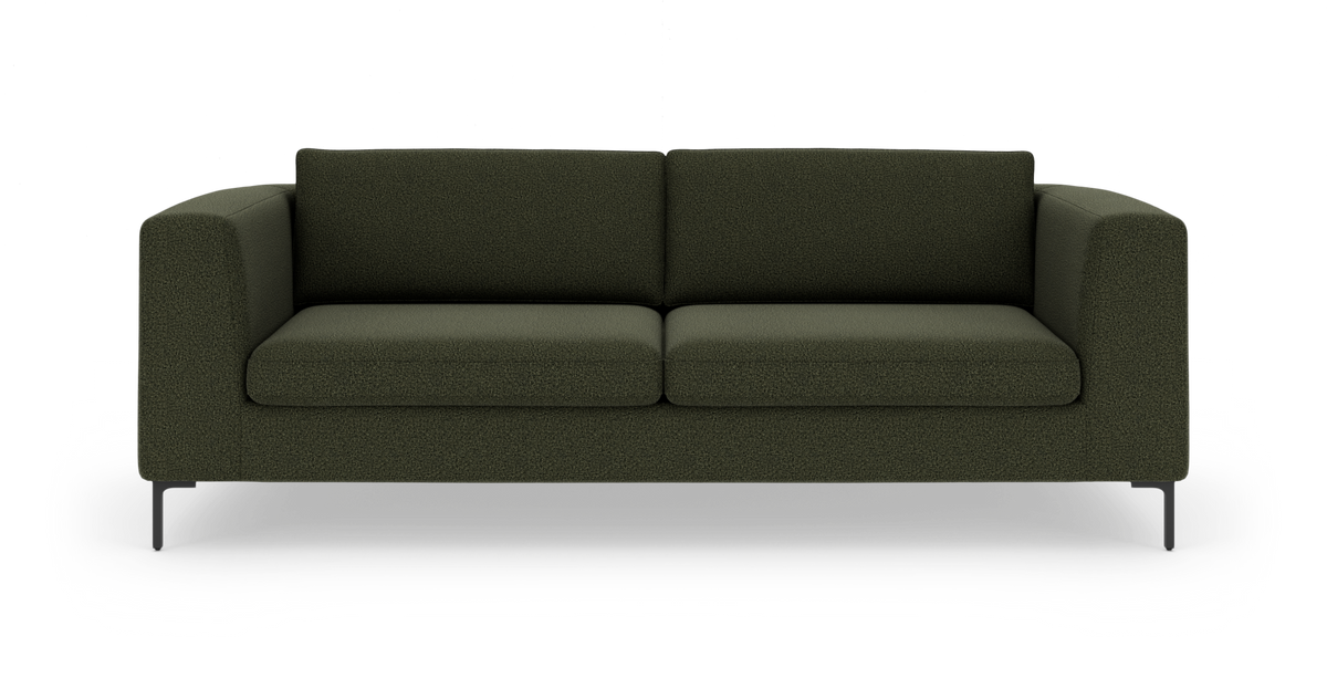 Mørkegrøn 3-personers sofa med bløde, blokformede armlæn og slanke sorte ben set forfra.