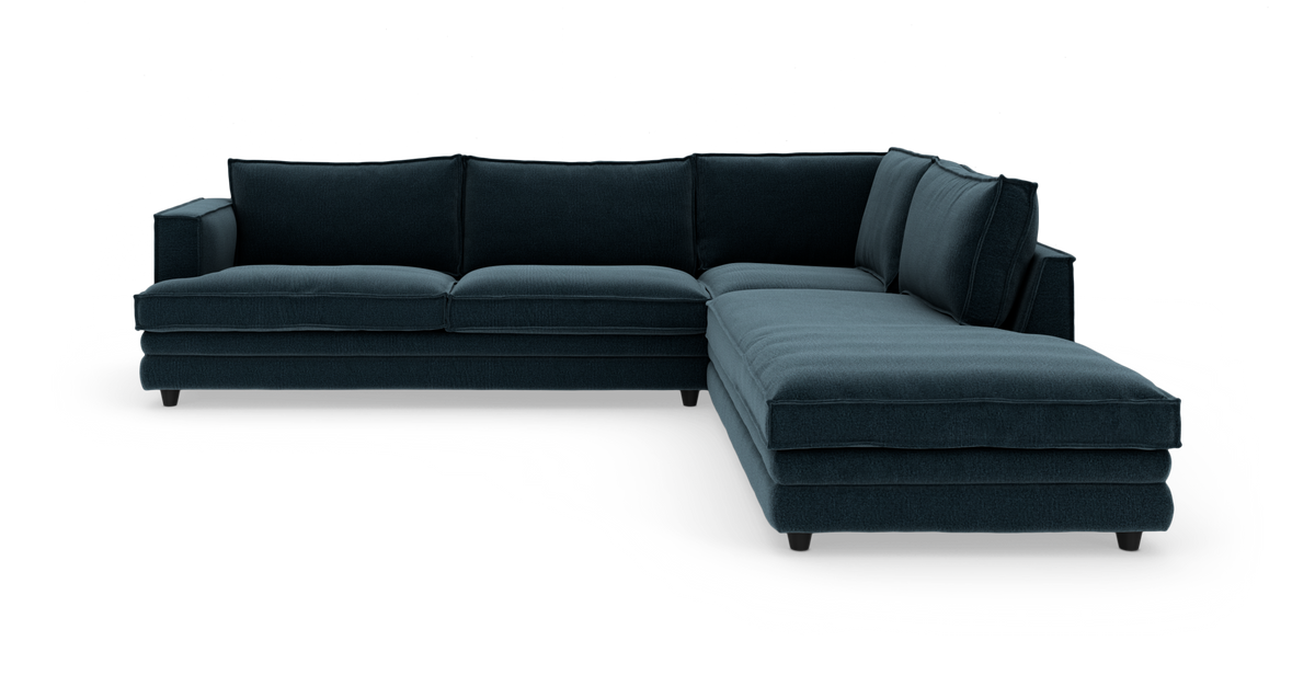 Mørk blå L‑sofa med chaiselong til højre, fritstående på hvid baggrund.