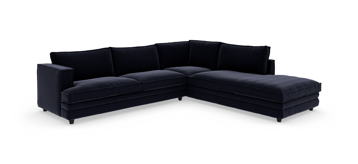 Mørkeblå L‑formet modulsofa med chaiselong, fritlagt på hvid baggrund.