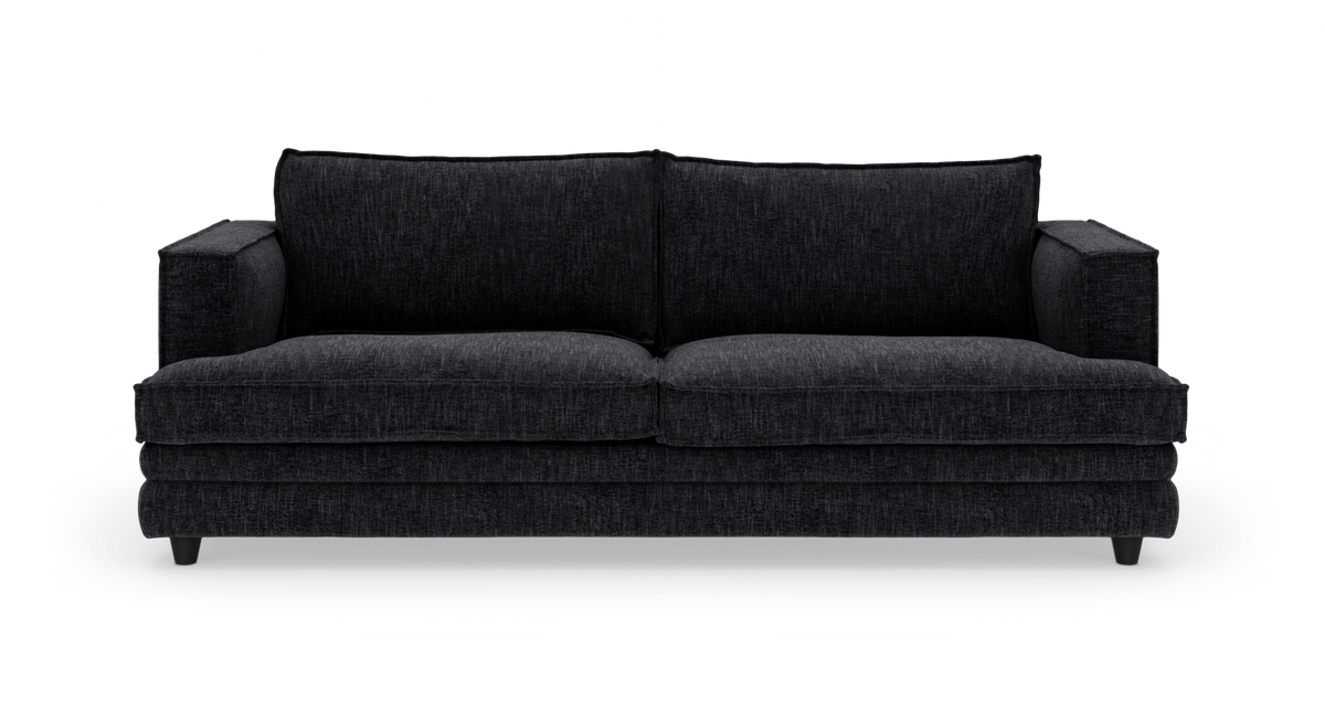 Mørkegrå tresæders sofa med brede armlæn og tykke sæde- og ryghynder, frilagt på hvid baggrund.