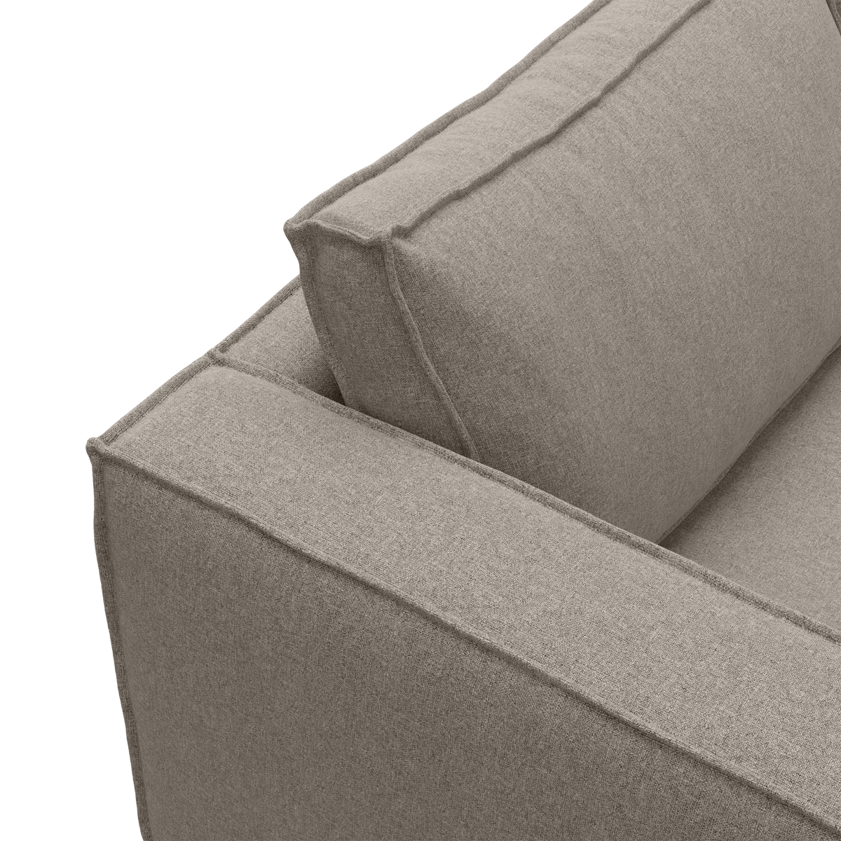 Nærbillede af beige sofa med kraftige ryg- og armlænspuder i tekstil.