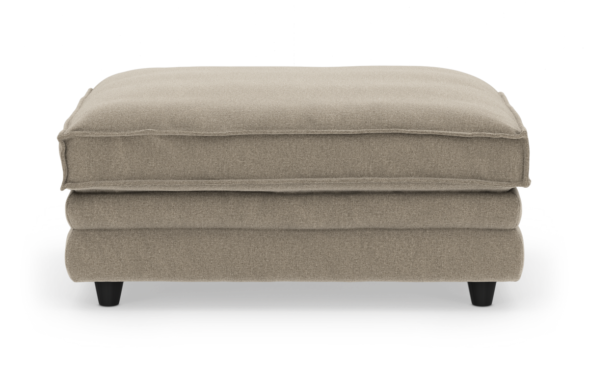 Beige polstret puf/ottoman på korte sorte ben, set forfra.