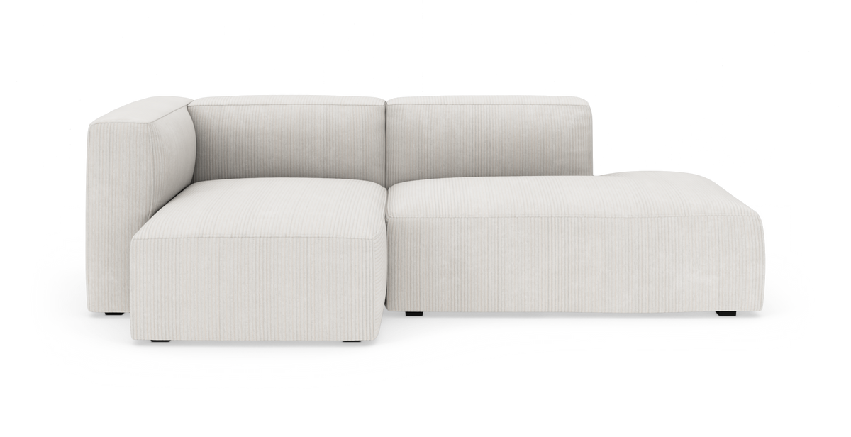 Lys beige modulsofa med venstre armlæn og højre chaiselong i riflede tekstil, frilagt på hvid baggrund.