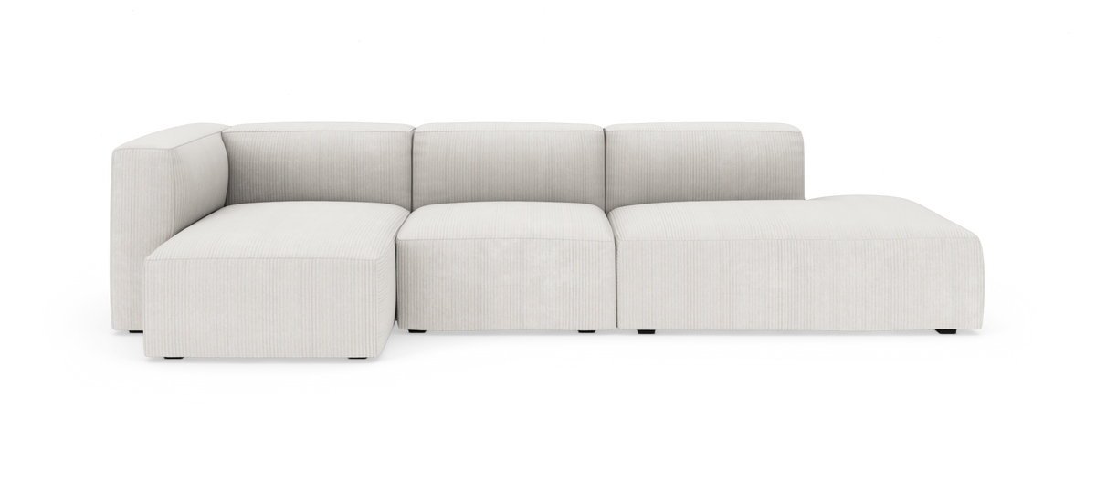 Lys beige modulsofa med chaiselong til højre i et minimalistisk studiobillede.