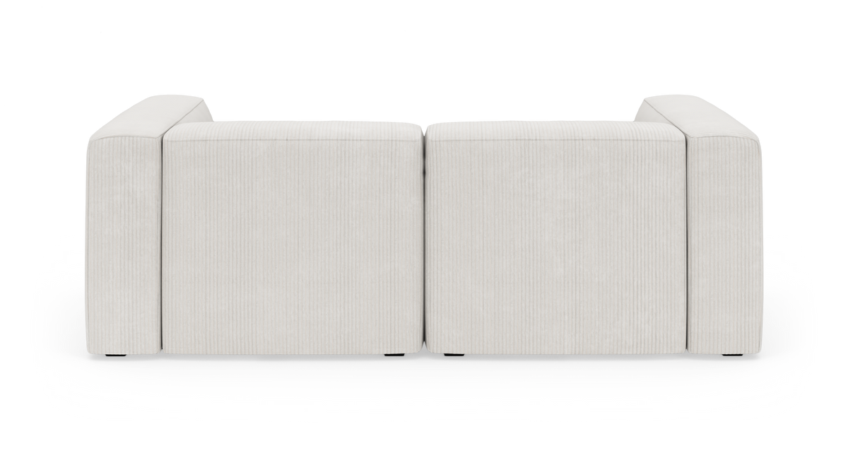 Lys beige 2-personers modulsofa med høje armlæn i rillet fløjl, frontvisning mod sort baggrund.