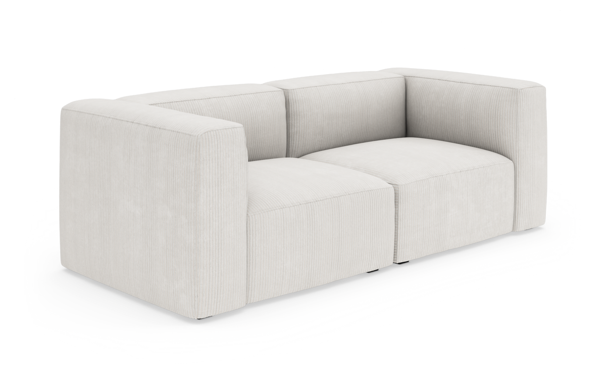 Lysebeige modulsofa med brede armlæn og rillet stofstruktur, frilagt på hvid baggrund.