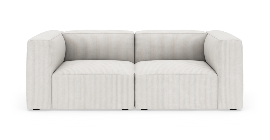 Lys beige modulsofa med brede armlæn, fritstående på hvid baggrund.