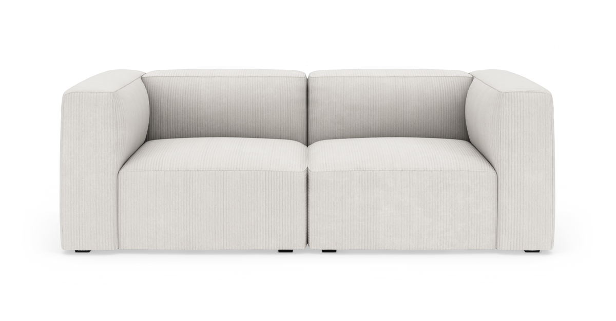 Lys beige modulsofa med brede armlæn, fritstående på hvid baggrund.
