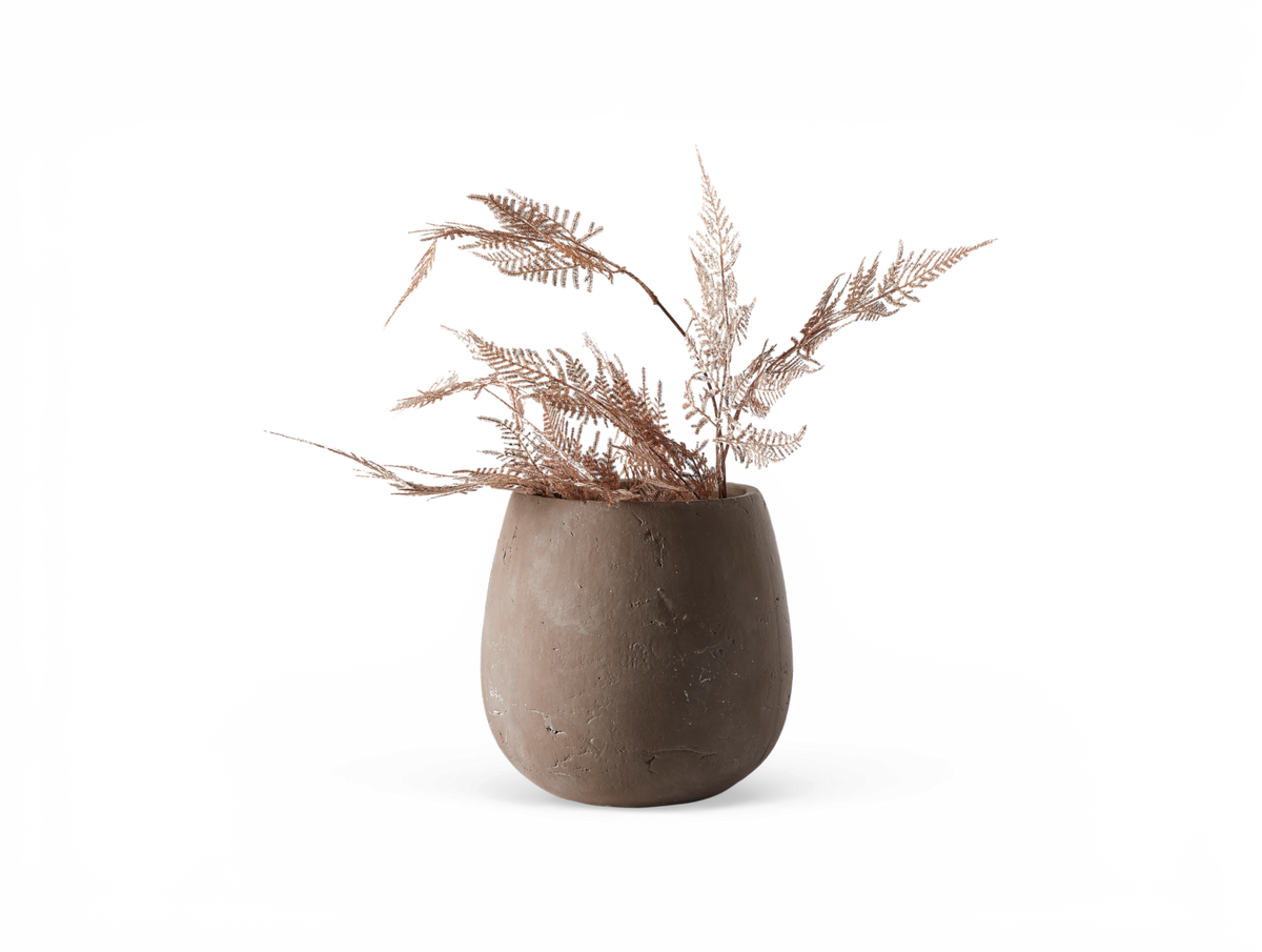 Beige keramisk vase med tørrede roséguldglitrende bregnegrene, frilagt.