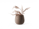 Beige keramisk vase med tørrede roséguldglitrende bregnegrene, frilagt.