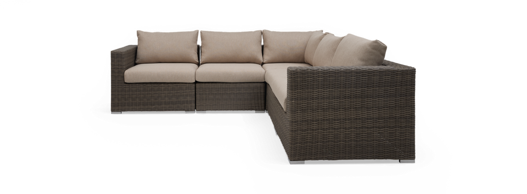 Modulær hjørnesofa i polyrattan med beige hynder, frilagt på sort baggrund.