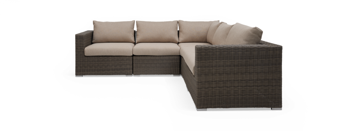 Modulær hjørnesofa i polyrattan med beige hynder, frilagt på sort baggrund.