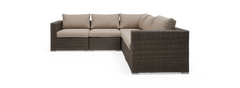 Modulær hjørnesofa i polyrattan med beige hynder, frilagt på sort baggrund.