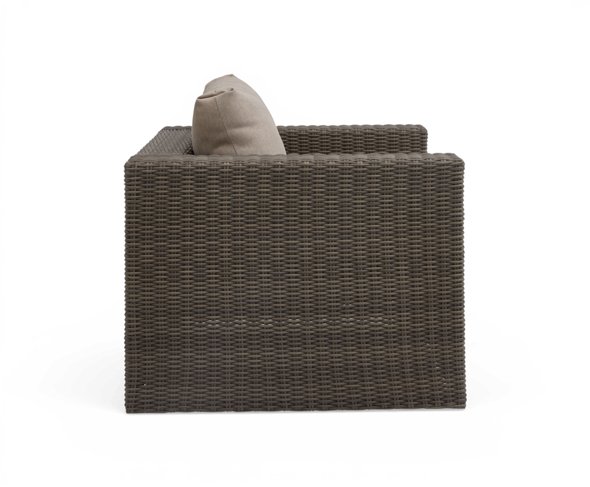 Sidevisning af brun rattan-lænestol med beige pude, fritlagt på hvid baggrund.