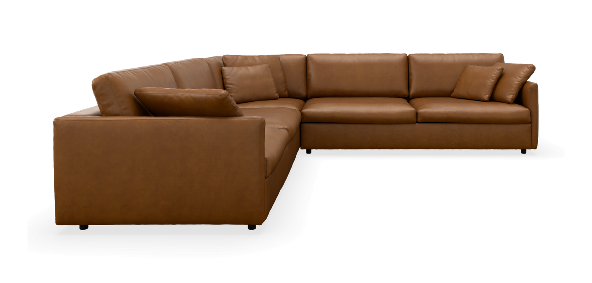 Brun L‑formet læderhjørnesofa med puder, frilagt på sort baggrund.
