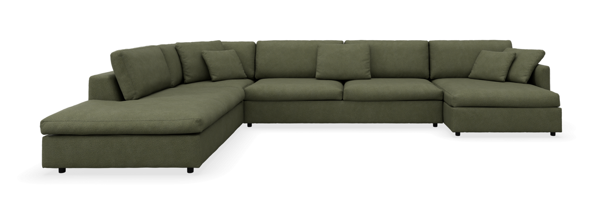 Grøn U‑formet hjørnesofa med chaiselong i begge ender, stofbetræk og løse puder.