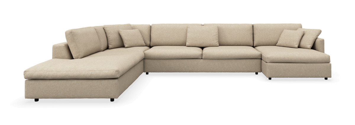 Beige U‑formet modulsofa med chaiselong i begge ender og løse ryghynder.