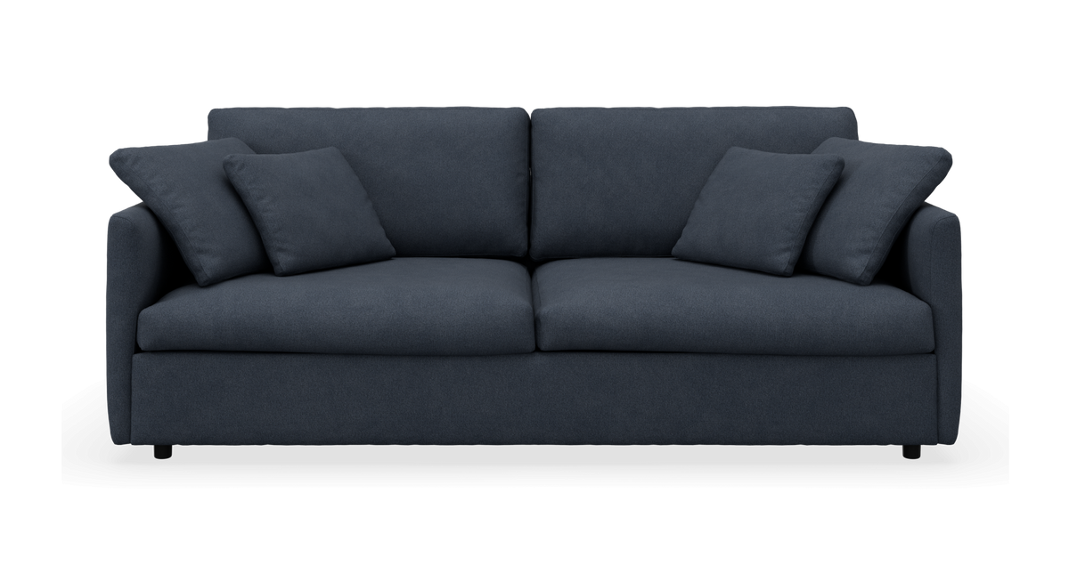 Mørkeblå sofa med fire puder, frontvisning, fritstående på neutral baggrund.