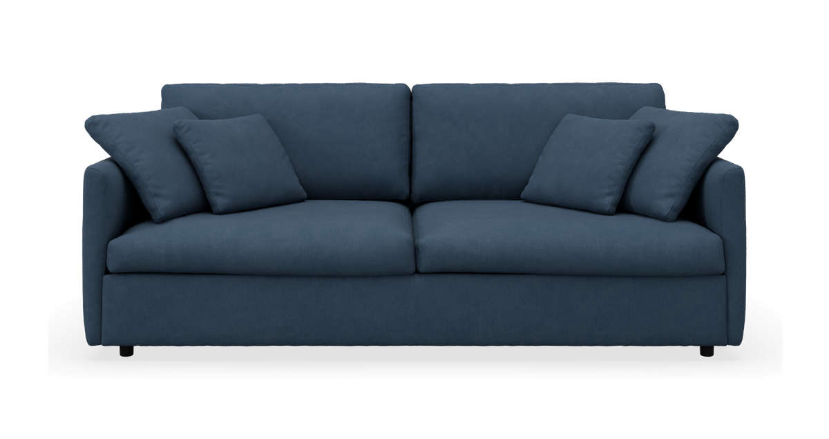 Blå 3-personers sofa med fire puder, set forfra på hvid baggrund.