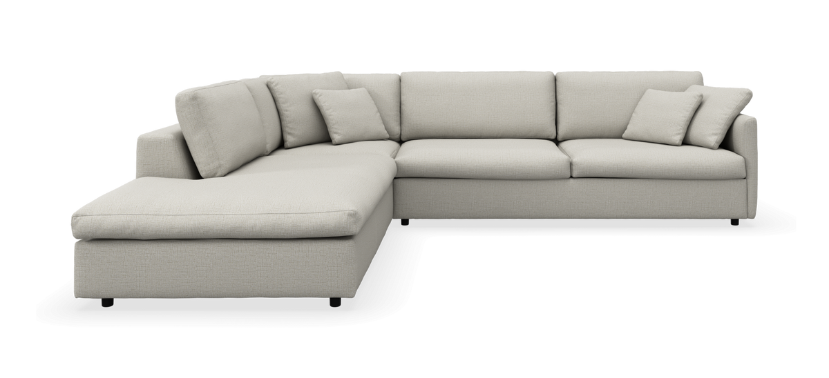 Beige L-formet modulsofa med venstrevendt chaiselong, tresæders del og løse puder, frilagt i studie.