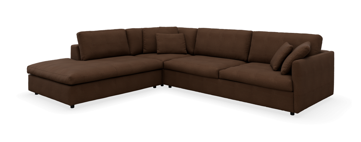 Brun L‑formet modulsofa med chaiselong til venstre og flere puder, frilagt mod sort baggrund.