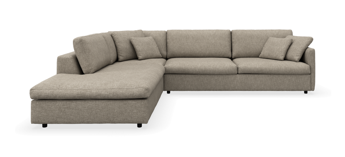 Beige L‑sofa med chaiselong og løse puder, frilagt frontvisning.