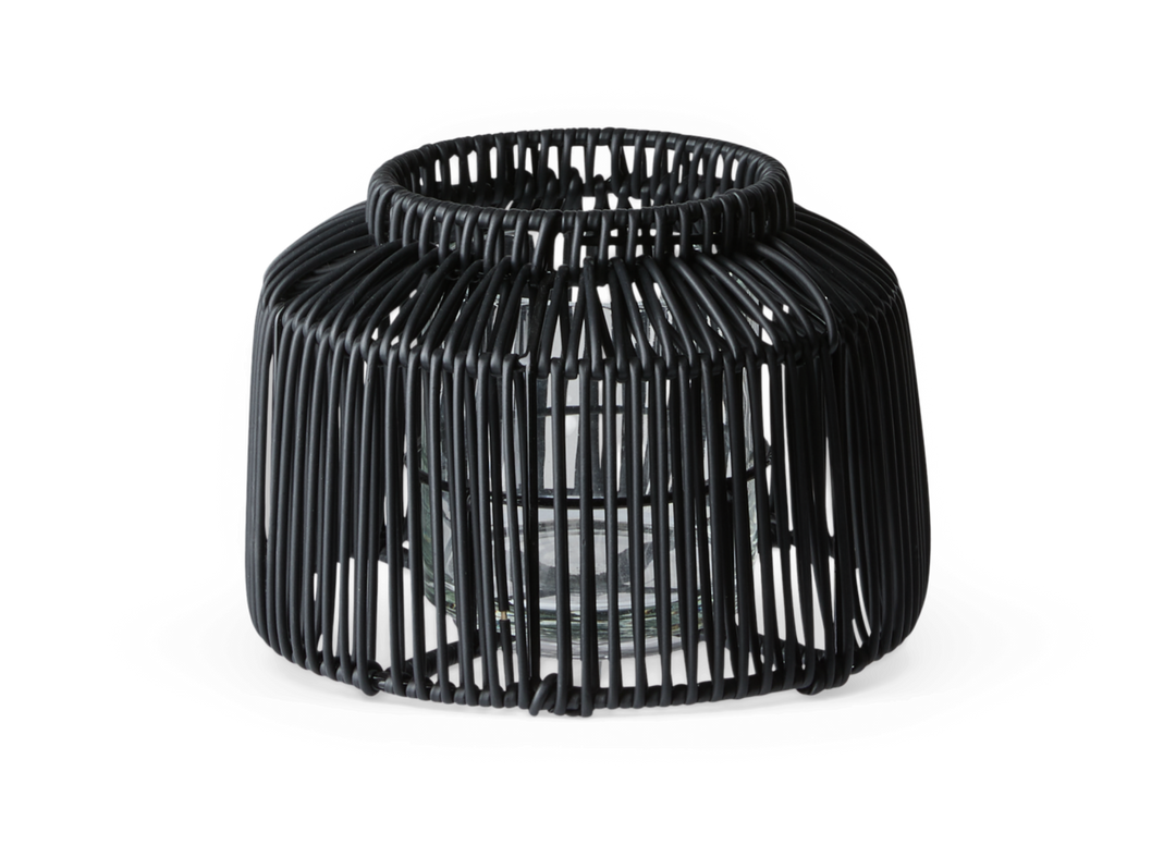 Sort rattan lyslygte med glasindsats til fyrfadslys, fritlagt på hvid baggrund.