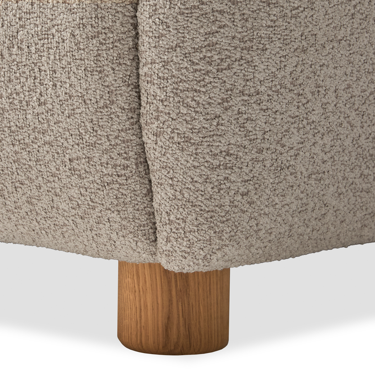 Nærbillede af sofa-hjørne i beige bouclé med rundt egetræsben.