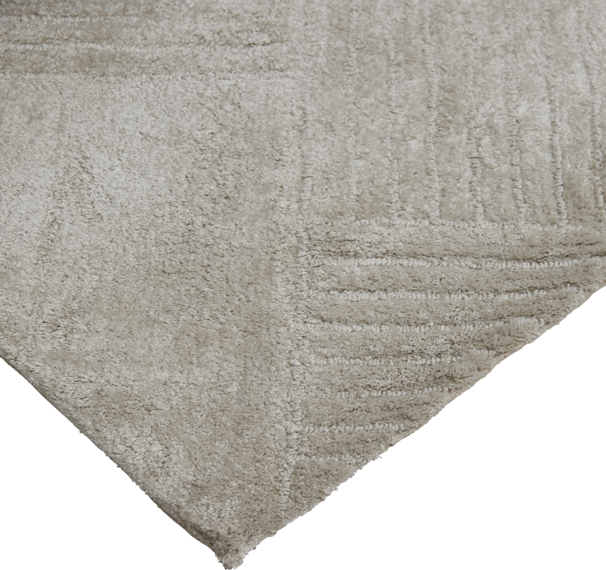 Beige, blødt ryatæppe med diskret geometrisk tekstur, vist fra et hjørne.