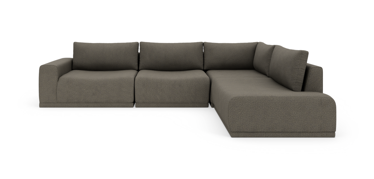 Modulsofa i L‑form med afrundede armlæn og bløde ryghynder i grå/taupe stof, frilagt på hvid baggrund.