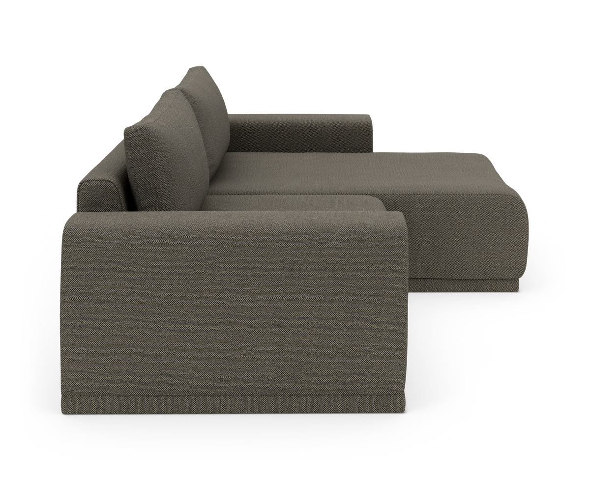 Mørkegrå modulsofa med chaiselong set fra siden på hvid baggrund.