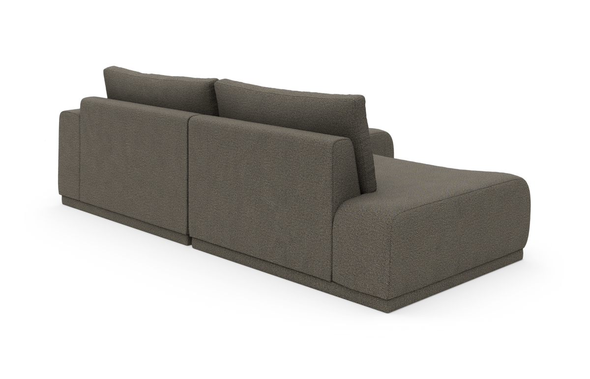 Modulsofa med chaiselong i gråt stof, vist skråt bagfra på hvid baggrund.